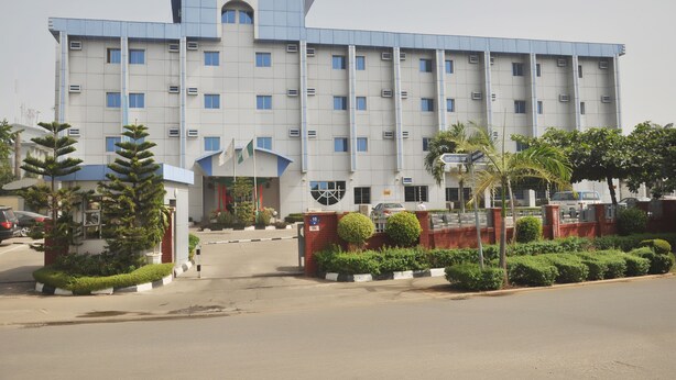 A large, multi-story hotel with a prominent entrance and a parking area. - Top Rank Hotel (Abuja)