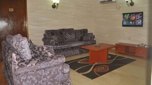 A living room with a sofa, a coffee table, and a TV on the wall. - Top Rank Hotel (Abuja)