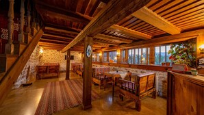 Interior rústico de madera con paredes de piedra, bancos de madera y un gran ventanal con vistas a la vegetación.