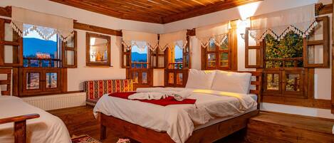 A traditional wooden room with a bed, a sofa, and a window with a view of a mountain.