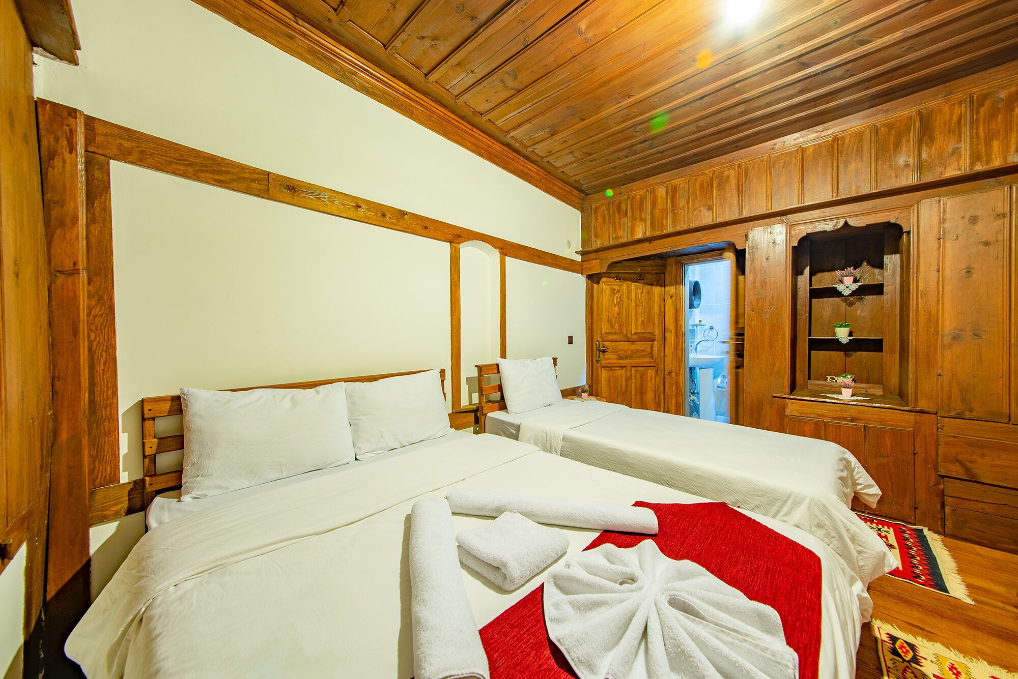 A room with two beds, wooden walls, and a wooden ceiling.