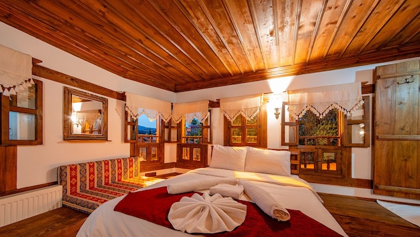 Una habitación tradicional de madera con una cama, un sofá estampado y vistas al exterior a través de ventanas.