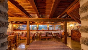 Un interior rústico con vigas de madera, paredes de piedra y un tapiz central.