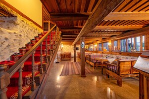 A wooden staircase with red carpeted steps leading to a stone wall.
