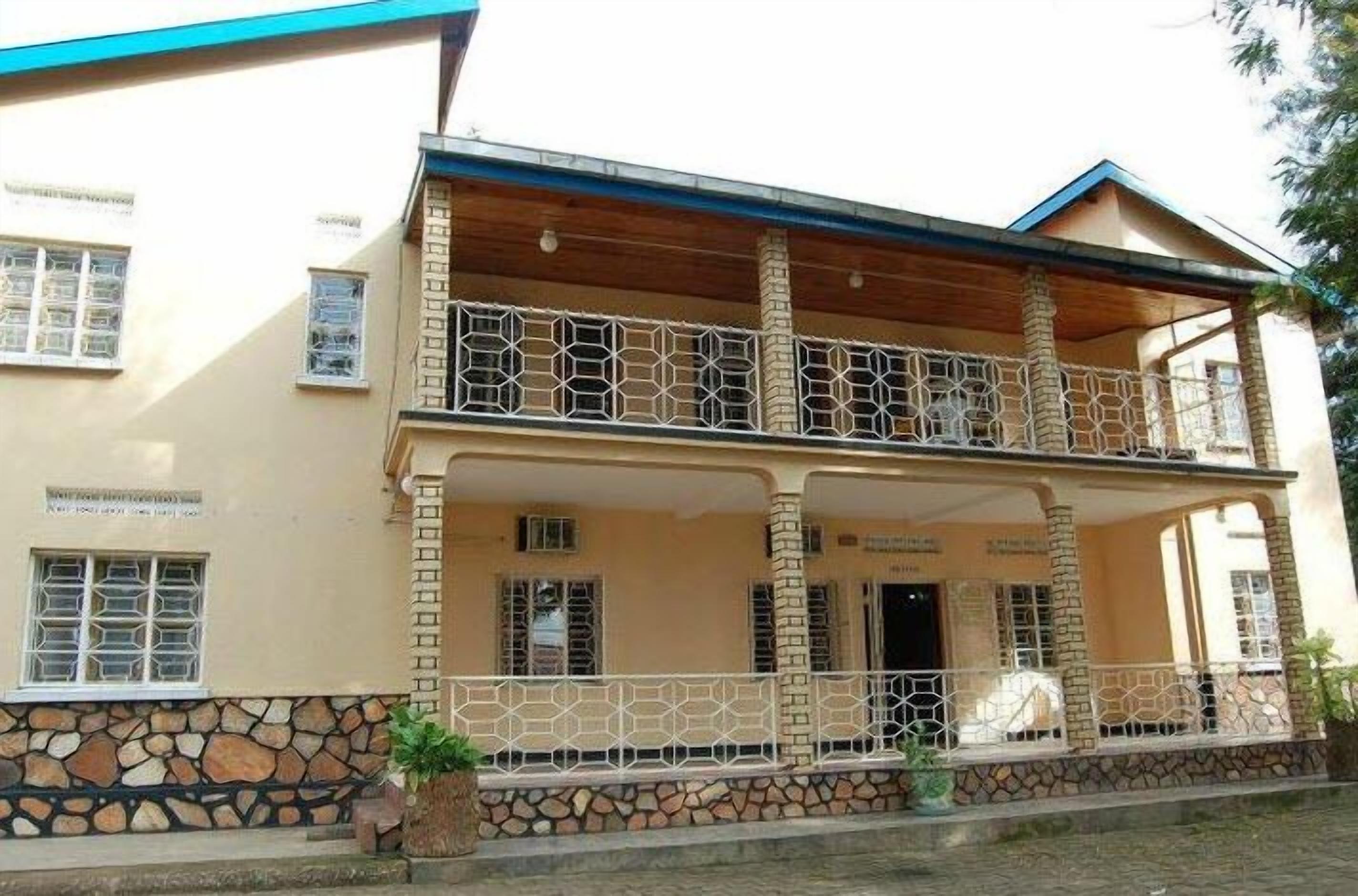 A two-story building with a balcony, stone foundation, and a wooden roof.