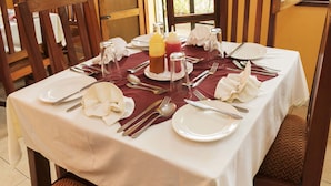 A dining table set with white tablecloth, red napkins, and silverware. - Rwenzori International Hotel (Kasese)