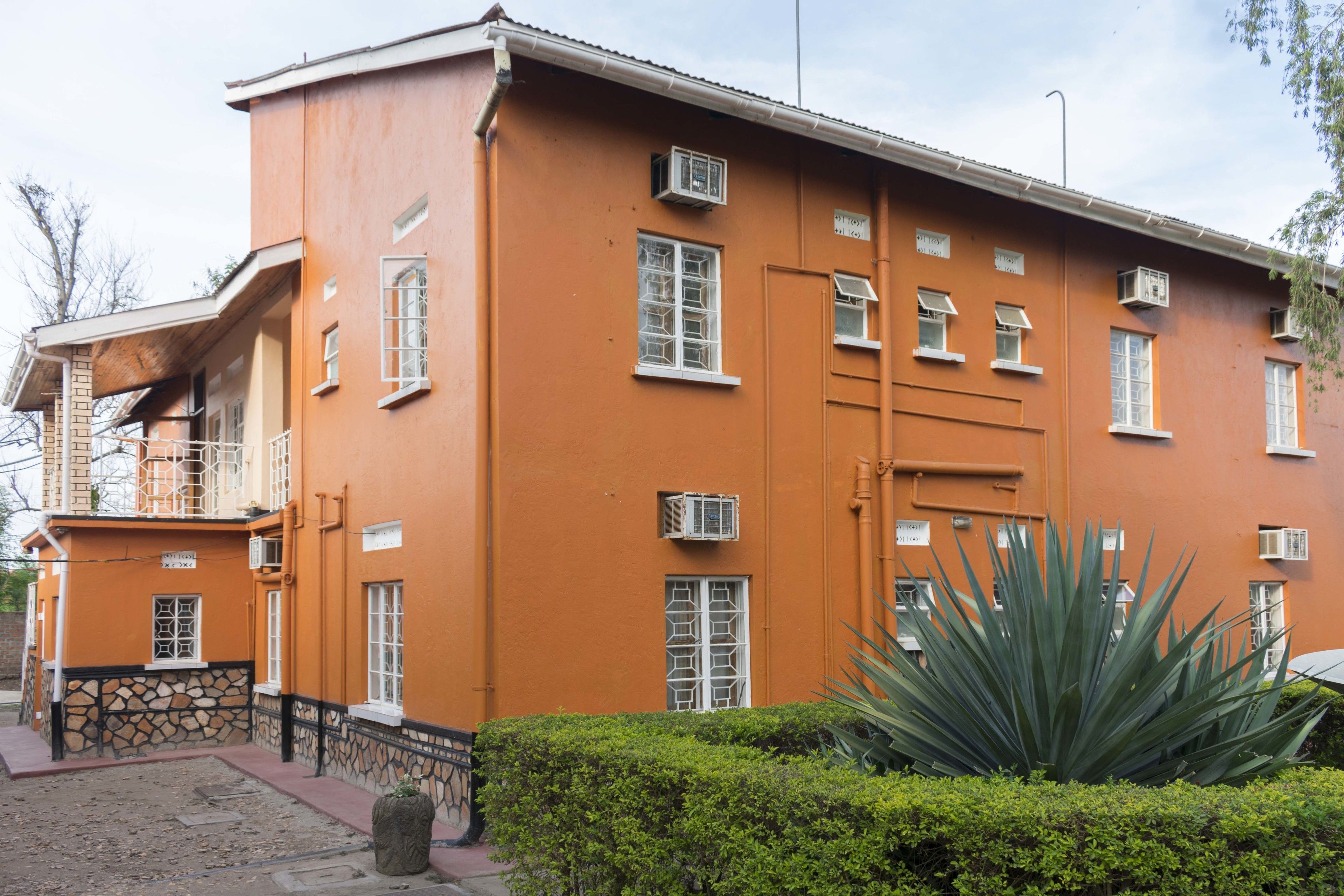 A multi-story building with a flat roof, multiple windows, and a small balcony.