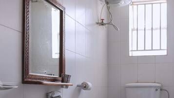A bathroom with a sink, mirror, toilet, and a window.