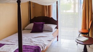 A four-poster bed with a canopy, a chair, and a small table in a room with a balcony view. - Rwenzori International Hotel (Kasese)
