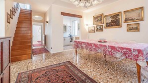 A dining area with a table set for four, a chandelier, and framed artwork on the wall.