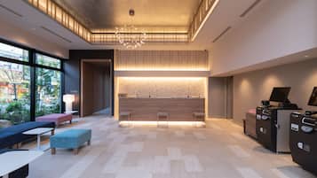 A modern lobby with a reception desk, seating area, and large windows.