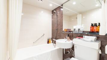 A modern bathroom with a bathtub, a sink, and a toilet. There are toiletries on the shelves and a mirror above the sink.
