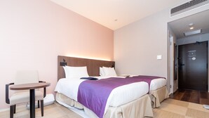 Une chambre d’hôtel avec deux lits, une petite table ronde et une chaise.