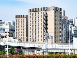 Un moderno edificio de hotel con varios pisos, grandes ventanales y un letrero llamativo.