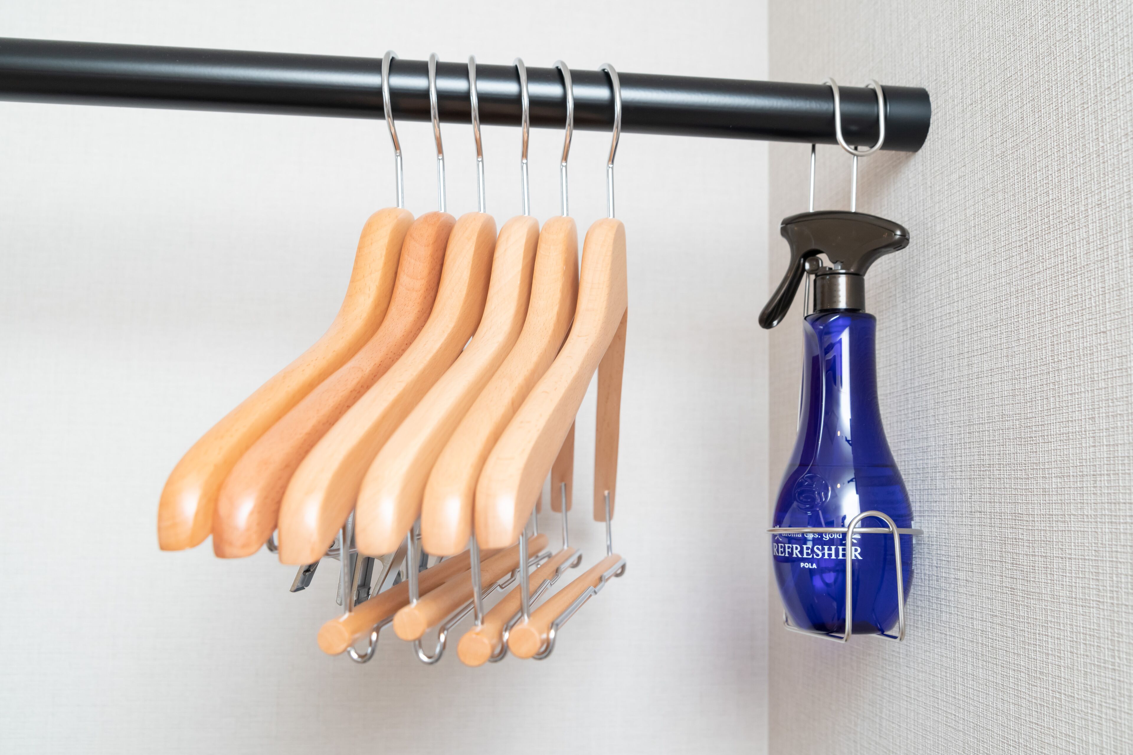 Ein Metallregal mit Holzaufhängern und einer blauen Sprühflasche an der Wand.