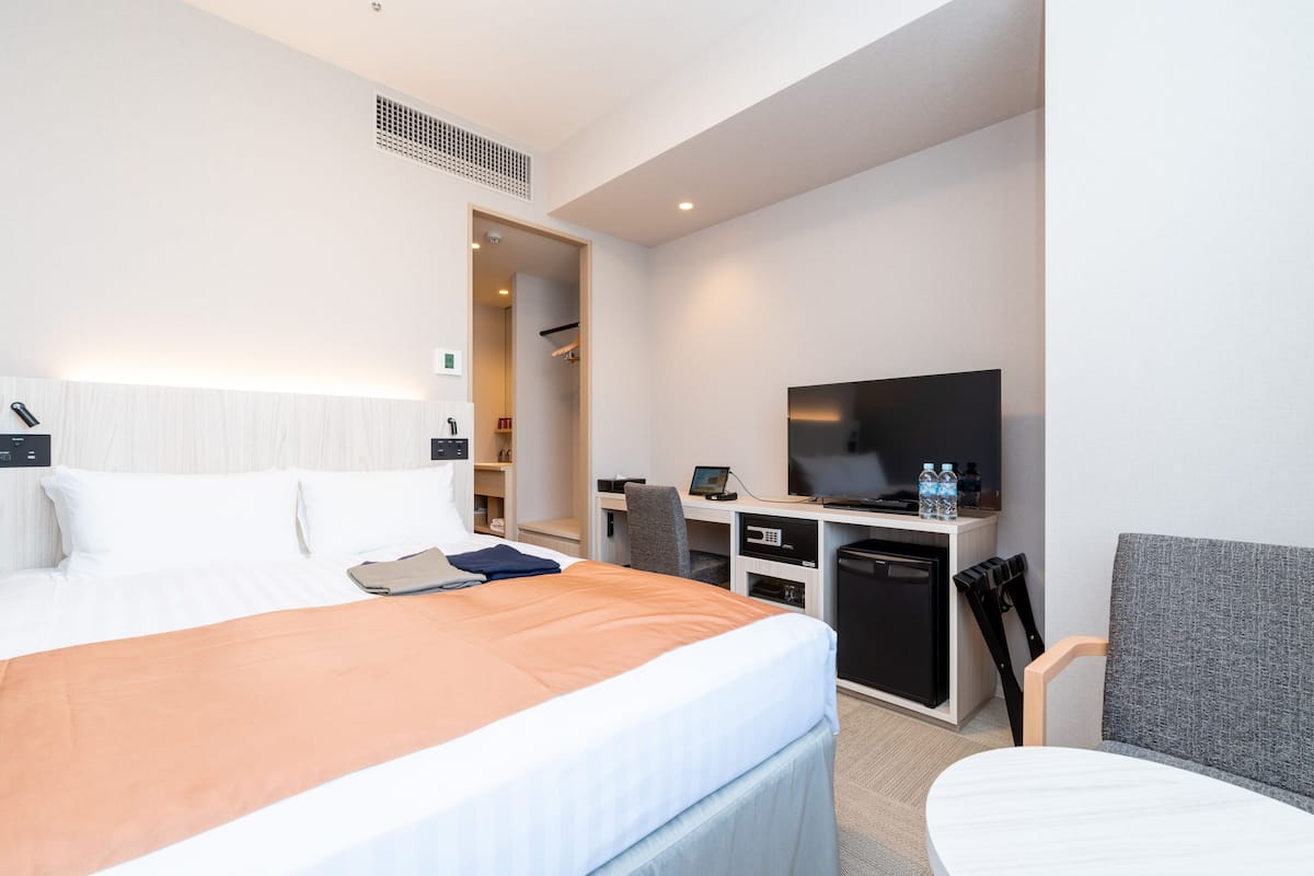 Ein Hotelzimmer mit Bett, Schreibtisch, Fernseher und Stuhl.
