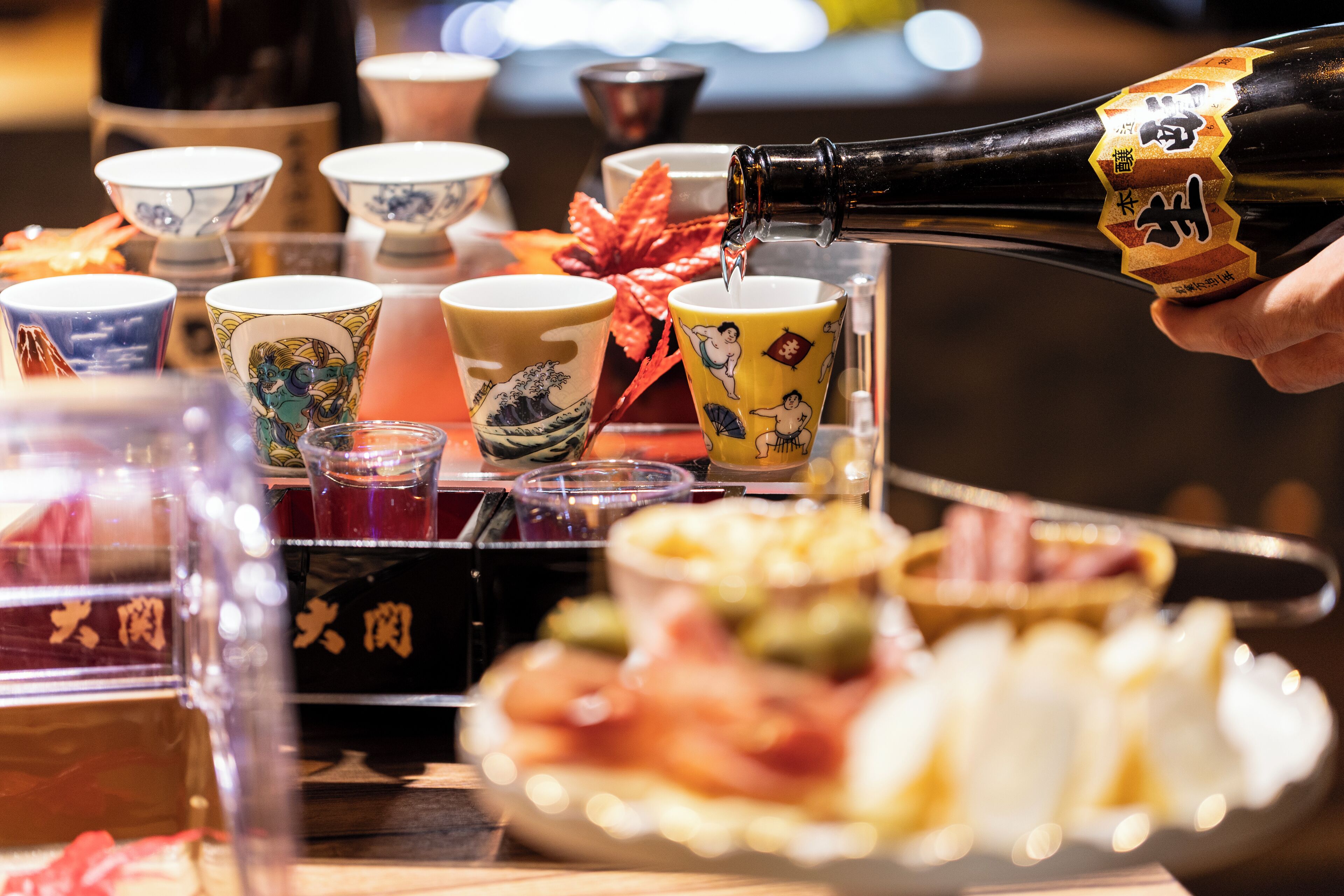 A person pouring a drink into a cup with a decorative label.