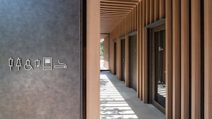 Un couloir avec des lambris en bois et des portes en verre, qui mène à un bâtiment.