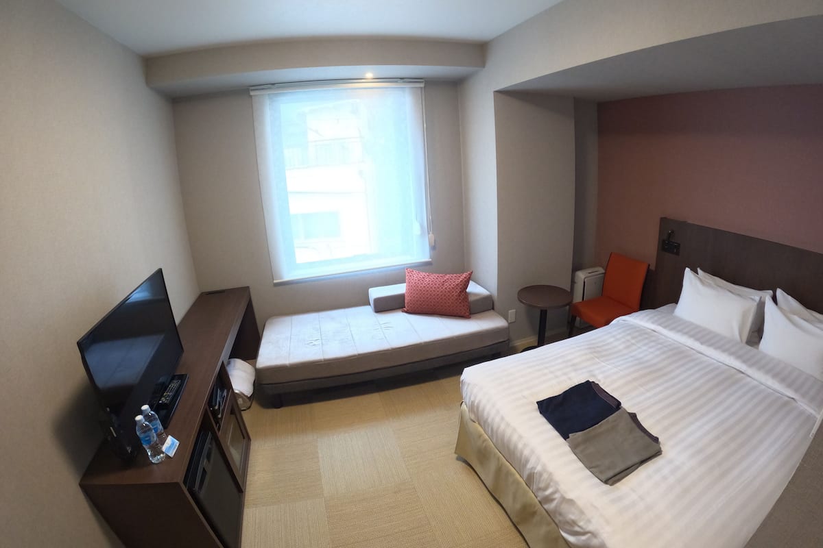 Ein Hotelzimmer mit Bett, Schreibtisch mit Computer, einem kleinen Tisch und einem Fenster mit Blick.