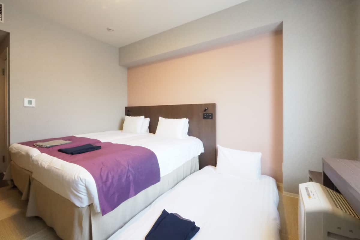 Ein Hotelzimmer mit zwei Betten, einem Schreibtisch und einem Heizkörper.