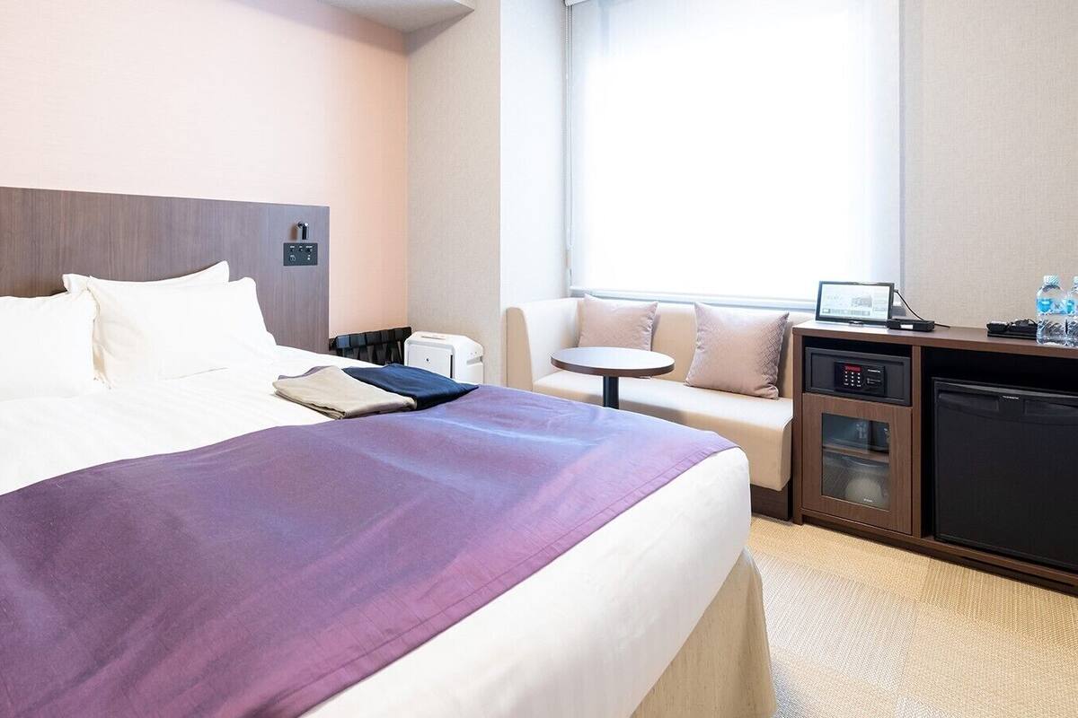 Ein Hotelzimmer mit Bett, Schreibtisch, Stuhl, kleinem Tisch, Mikrowelle und Minikühlschrank.
