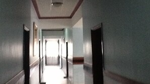 A long, narrow hallway with a high ceiling and a light fixture. - Serene Hotel (Mbarara)