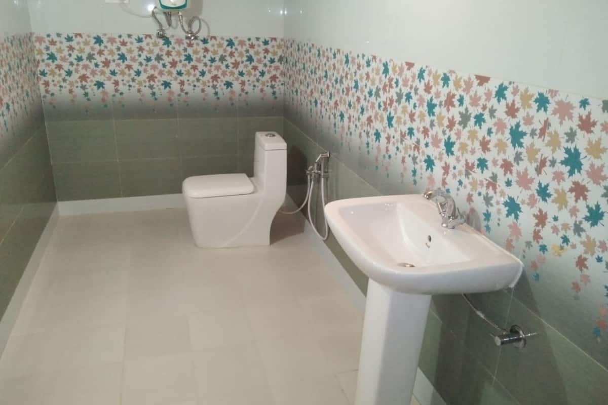Une salle de bain avec des toilettes, un lavabo et des murs carrelés.