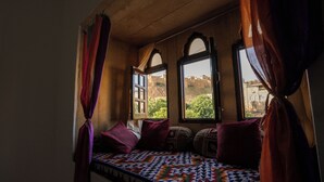 Ein Zimmer mit einem Bett, zwei Fenstern und Blick auf Gebäude.