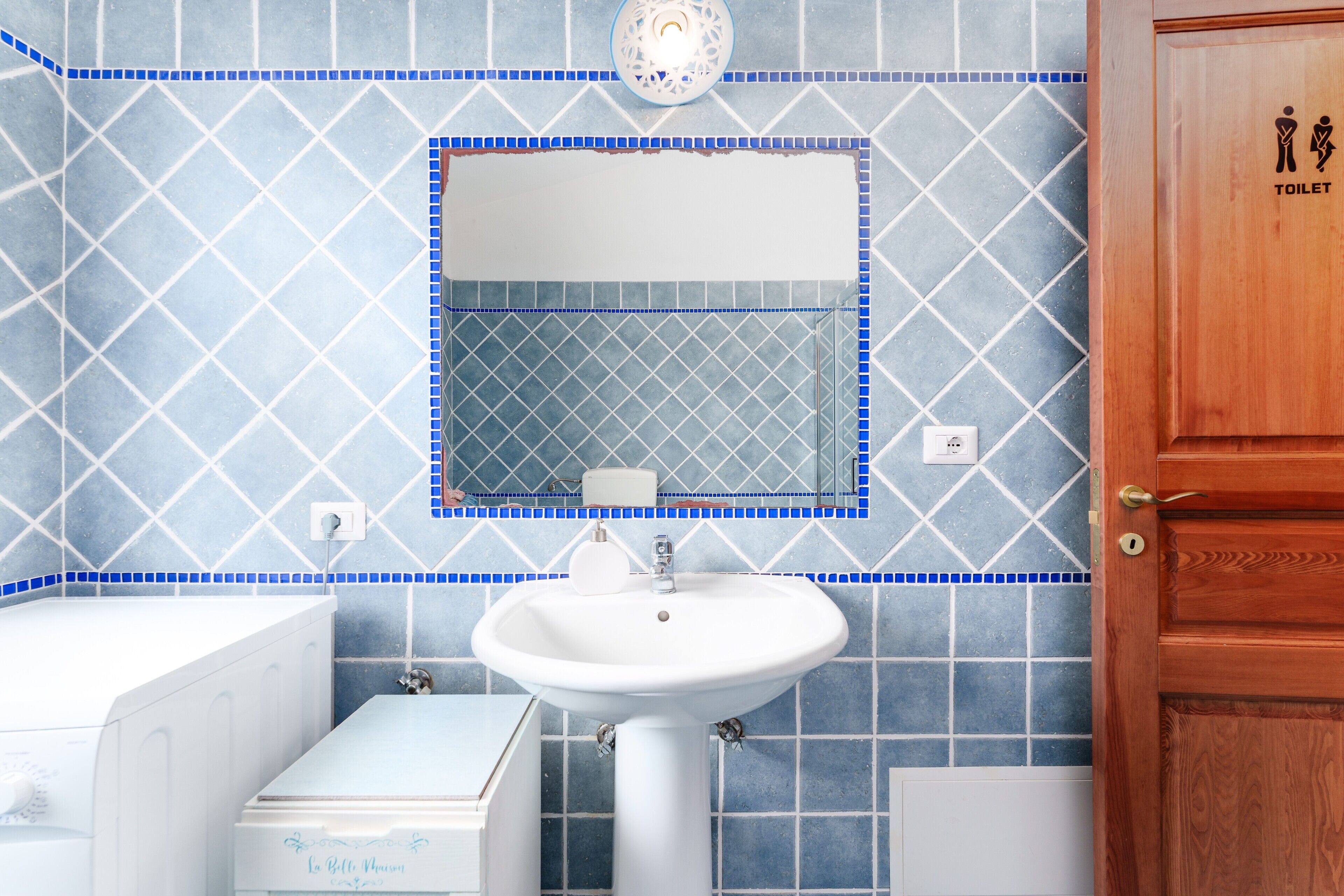 Un baño con lavamanos blanco, espejo y retrete.