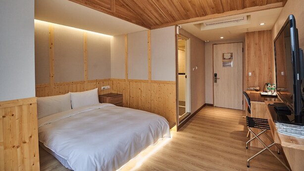 A wooden-paneled bedroom with a bed, bedside table, and a desk with a chair. - Chillax Inn (Kaohsiung)