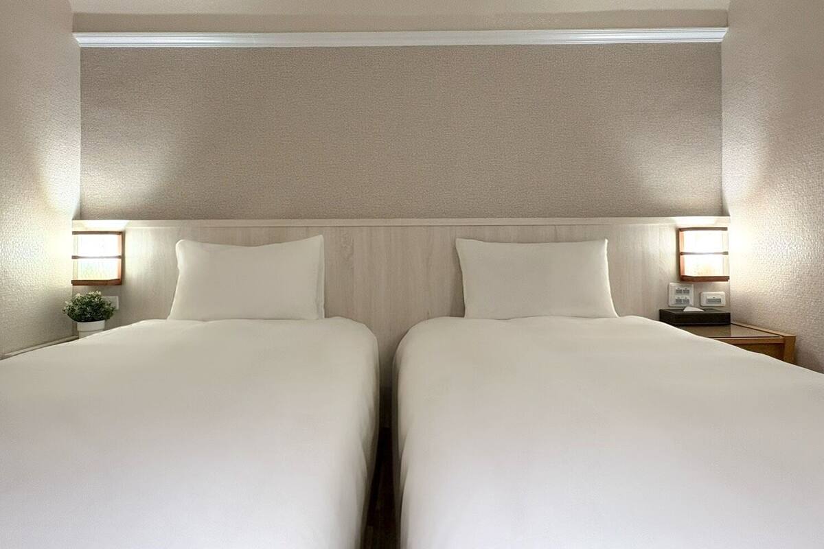 Une chambre avec un grand lit pour deux personnes, deux tables de chevet, chacune équipée d’une lampe et d’une petite plante.