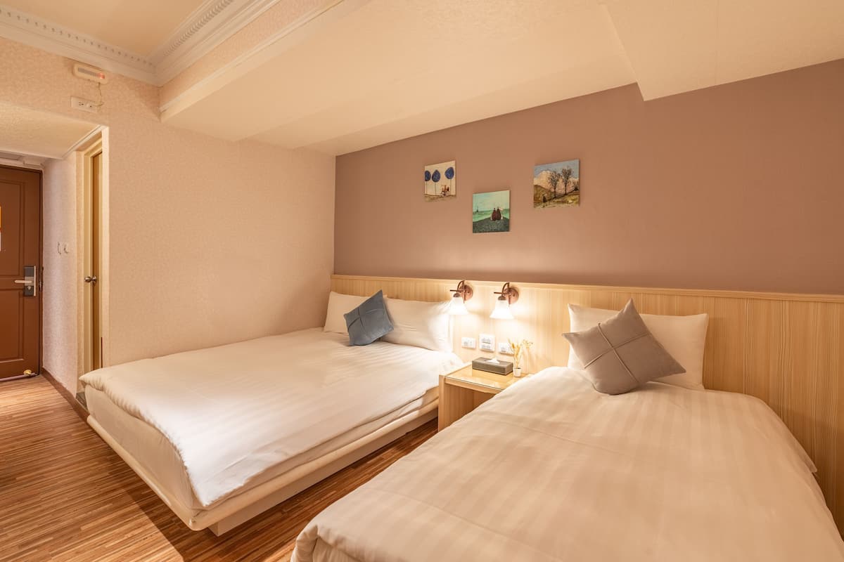 Une chambre d’hôtel avec deux lits, une tête de lit en bois, une table de chevet avec une lampe et des œuvres d’art murales.