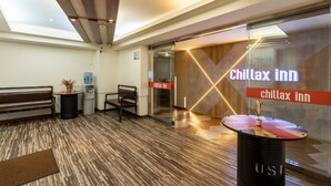 A lobby with a reception desk, seating area, and a glass door entrance labeled "Chillax inn". - Chillax Inn (Kaohsiung)
