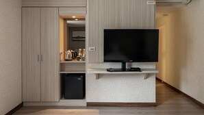 A compact living space with a built-in TV, a small fridge, and a kitchenette area. - Chillax Inn (Kaohsiung)