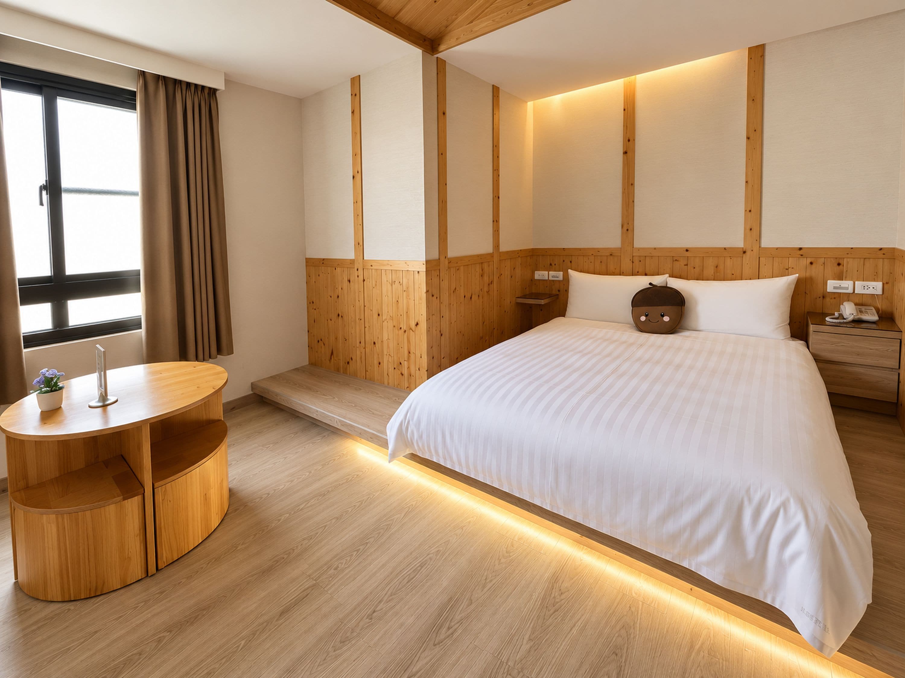 Hotellihuone, jossa on suuri sänky, puupanelointi, yöpöytä lampulla sekä pieni oleskelualue, jossa on pöytä ja tuoli.