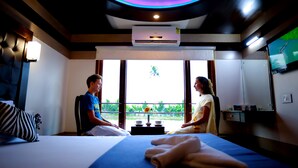 Ein Zimmer mit einem Bett, einer Massageliege, einem Masseur und einem Klienten.