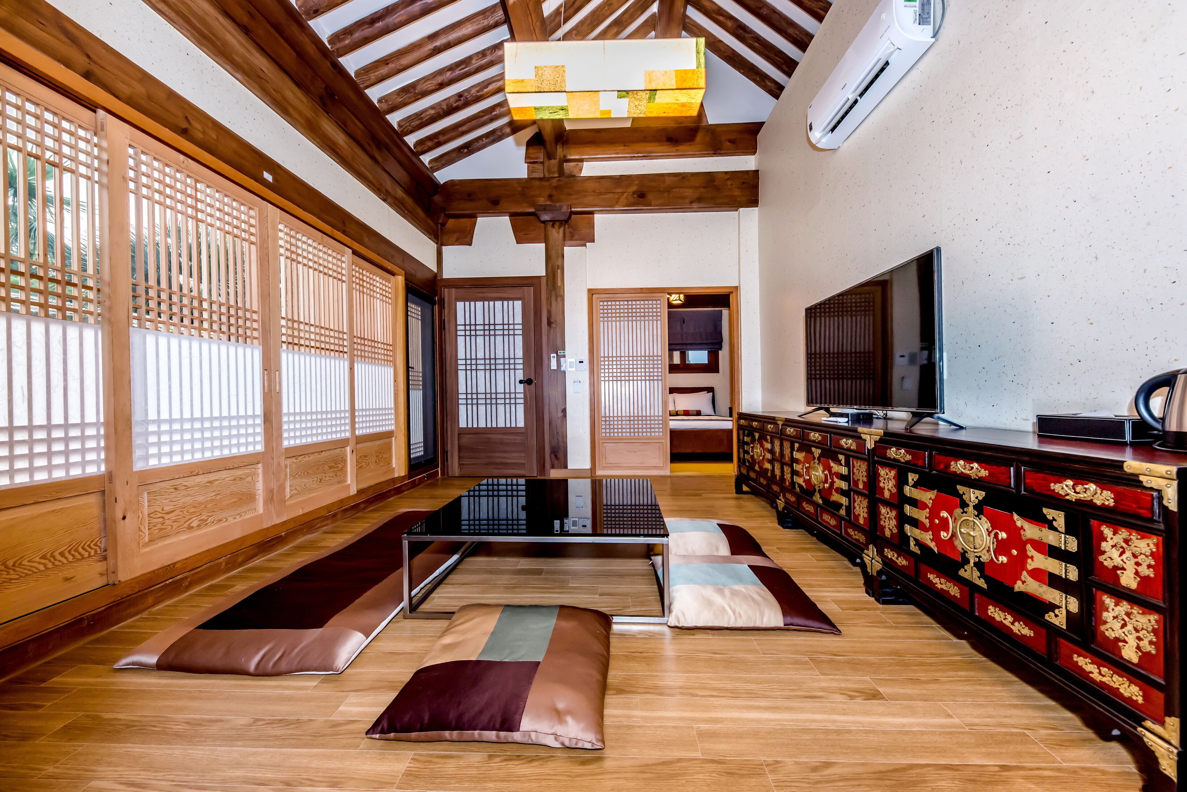 Ett traditionellt japanskt rum med tatamimattor, ett lågt träbord och en tv som står på ett skåp.