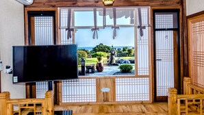 Una habitación tradicional japonesa con suelo de tatami, televisión y vistas a un jardín a través de paneles shoji.
