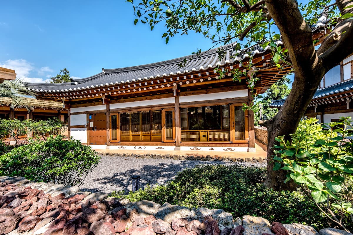 Un edificio japonés tradicional con techo de tejas, vigas de madera y un camino de piedra que conduce a la entrada.