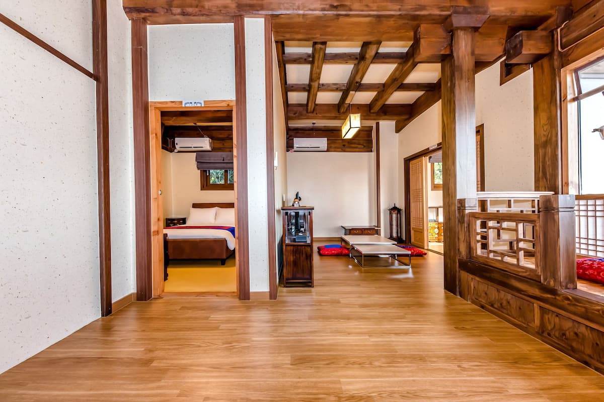 Una habitación amplia con vigas de madera, una cama, una mesita y un ventanal con vistas.