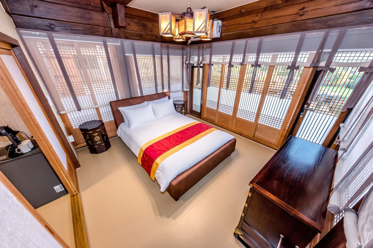 Una habitación de madera con una cama, un escritorio y vistas amplias a través de ventanas grandes.