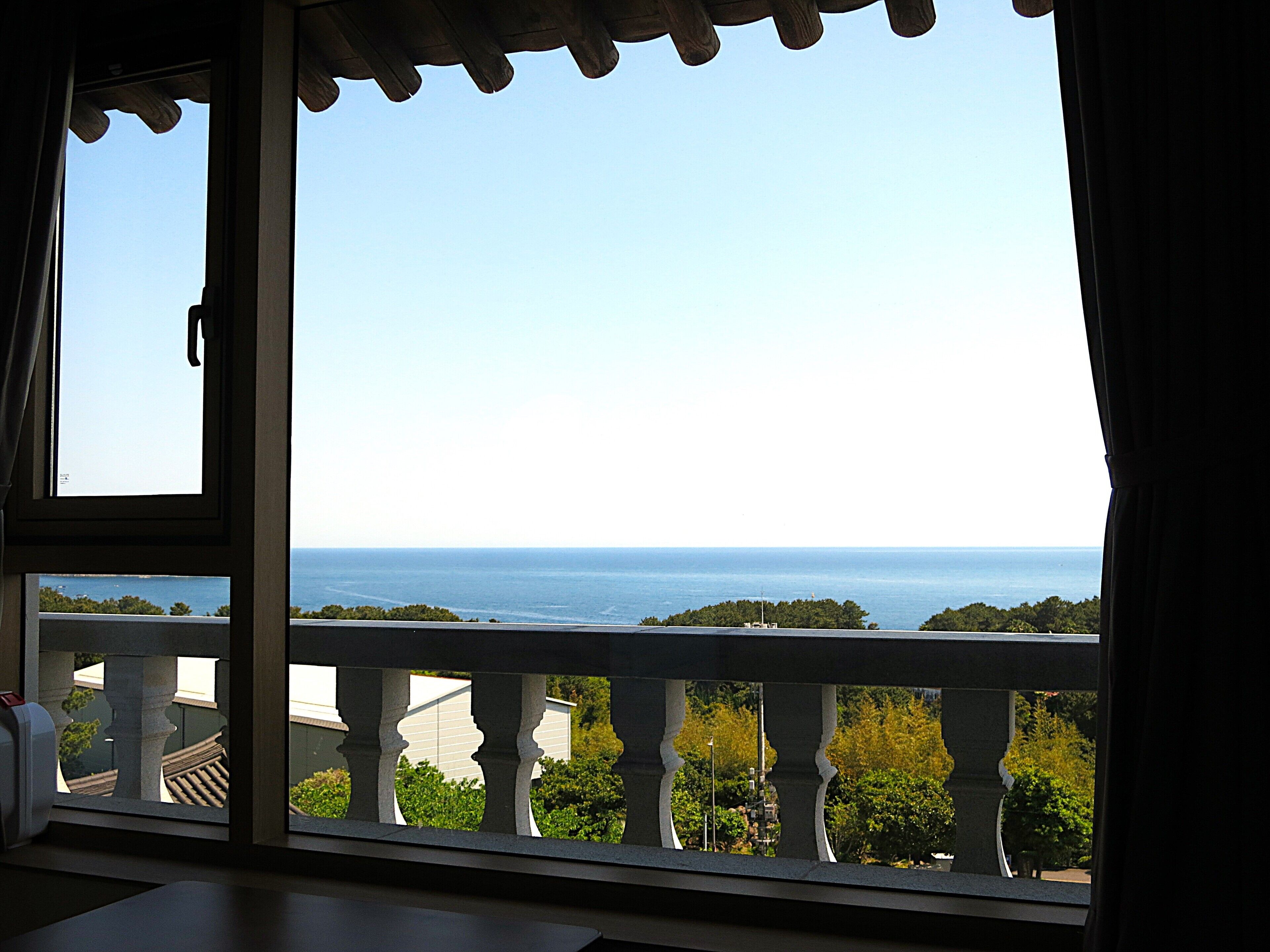 Uma varanda com vista para o mar e vegetação.