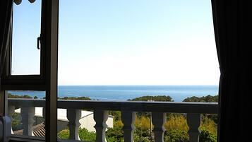 Uma varanda com vista para o mar e vegetação.