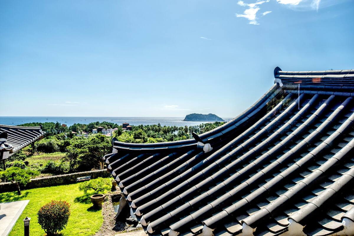 Tejado coreano tradicional con vista a un paisaje costero.