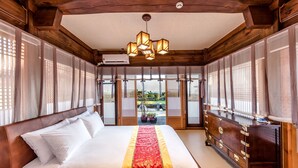 Una habitación tradicional japonesa con una cama grande, muebles de madera y puertas correderas que dan a un jardín.