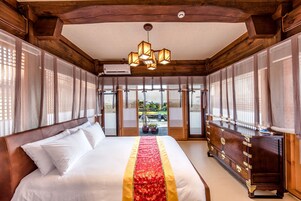 Una habitación tradicional japonesa con una cama grande, muebles de madera y puertas correderas que dan a un jardín.