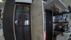 A modern kitchen with a built-in refrigerator, a glass door cabinet, and a shelf with various bottles and decorative items. - Hotel Imaginarium (Tbilisi)