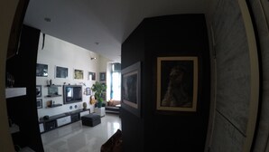 A modern living room with a flat-screen TV, a coffee table, and a sofa. There are several framed pictures on the walls and a potted plant. - Hotel Imaginarium (Tbilisi)