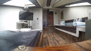 A compact, modern room with a bed, a small desk, a television, and a seating area with cushions. - Hotel Imaginarium (Tbilisi)