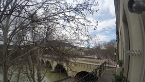 A view from a balcony overlooking a bridge with arches, a river, and a distant building. - Hotel Imaginarium (Tbilisi)